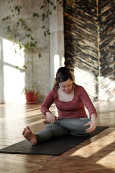 A woman with Down syndrome stretches on a yoga mat in a peaceful, sunlit room.