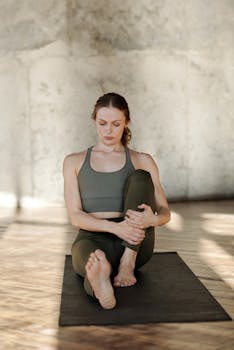 A woman practices yoga indoors, promoting flexibility and wellness.