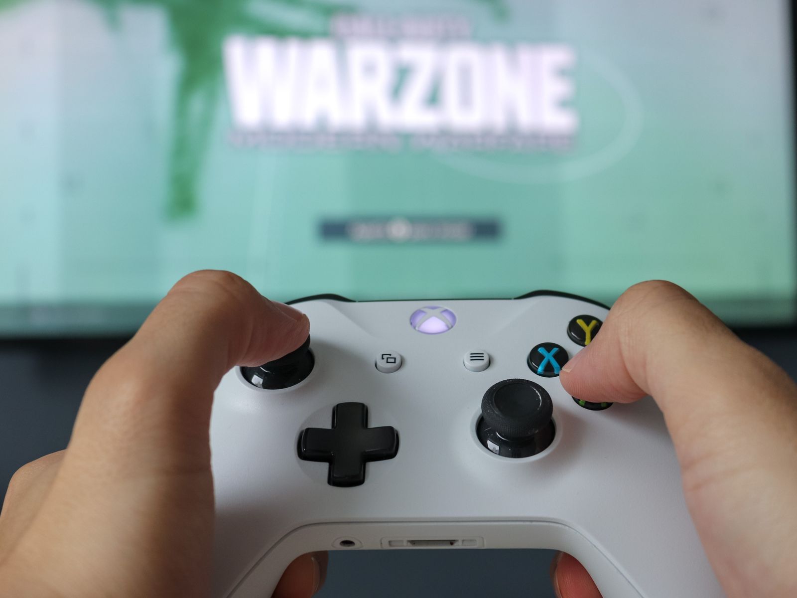 Hands using a game controller in front of a game screen