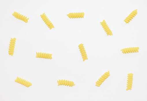 Artistic flat lay of fusilli pasta pieces arranged on a clean white background, highlighting simplicity and style.