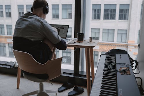 Man in Gray Shirt Sitting on Chair in Front of Computer