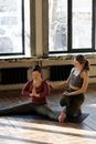 在室内，一名女士在私人教练的帮助下练习瑜伽伸展姿势