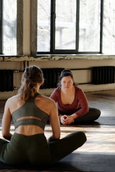 Two women practicing yoga indoors, promoting inclusivity and mindfulness.