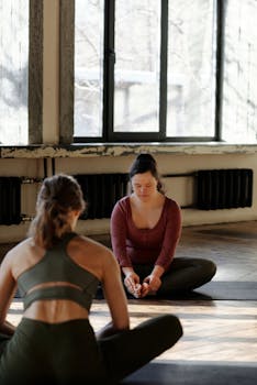 Two women practicing yoga in a calm indoor setting, focusing on relaxation and wellness.
