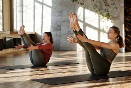 Two women practicing yoga in a bright indoor studio, focusing on strength and balance.