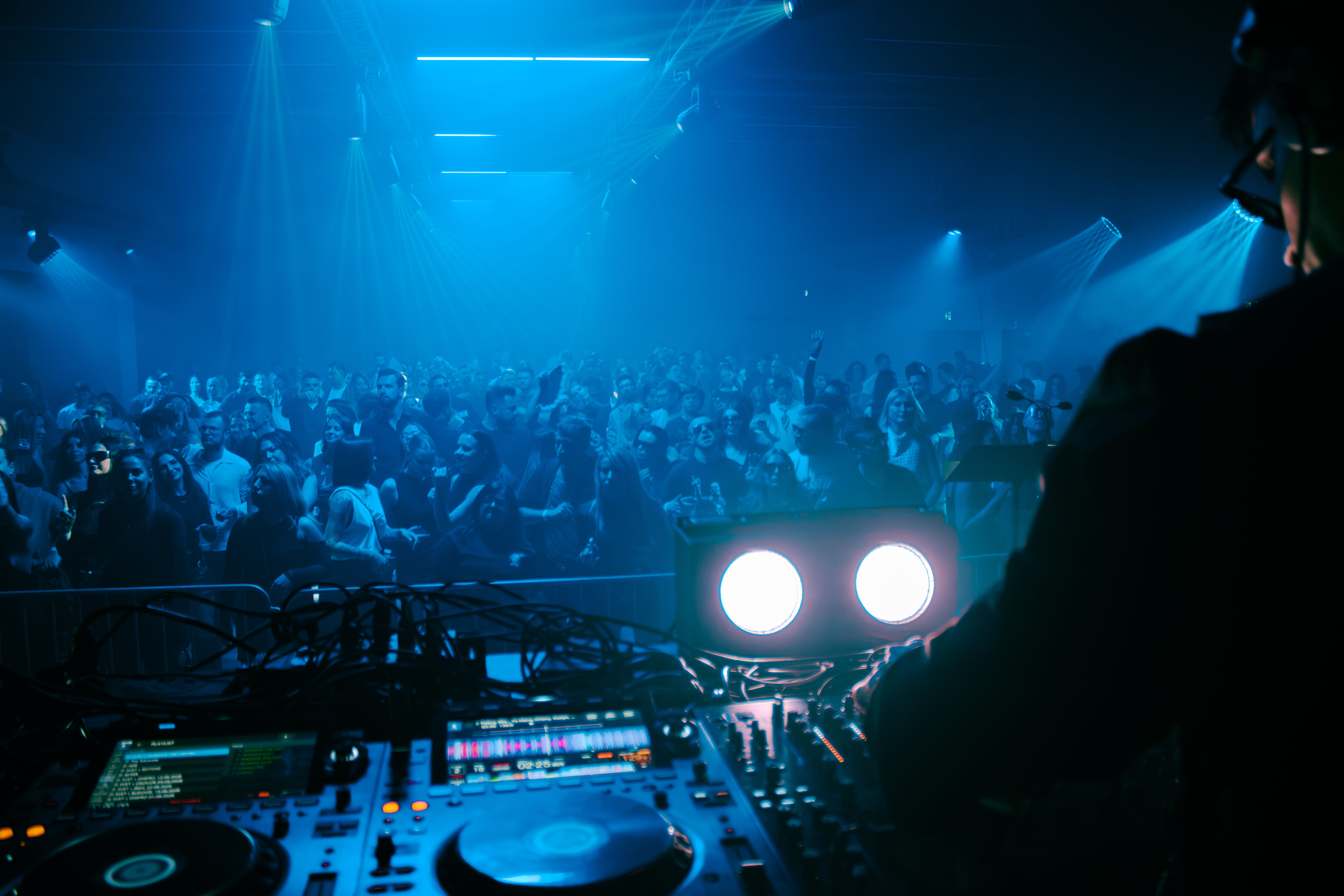 Energetic DJ set in a crowded Polish nightclub with vibrant blue lighting.
