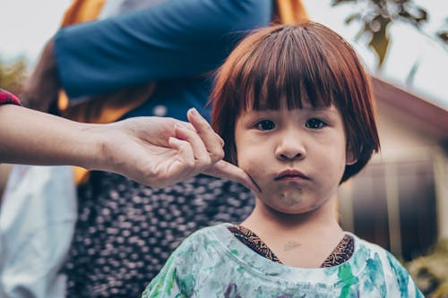 Selective Focus Photo of a Person Touching a Cute Kid's Cheek