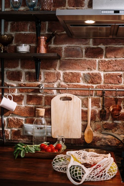 Free Cozy kitchen setting with chopping board, vegetables, and a brick wall background. Stock Photo