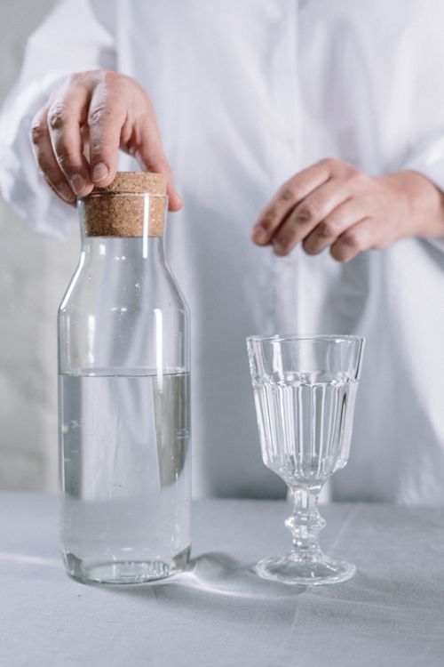 Free Elegant still life of hands with glass and water jug on table. Stock Photo