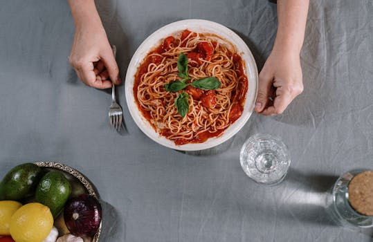Top view of a fresh Italian pasta dish with vegetables on a table setting.