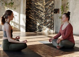 Two women meditating indoors for relaxation and wellness.