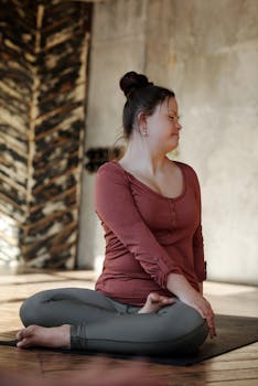 A young woman with Down syndrome practicing yoga indoors, embracing a healthy lifestyle.