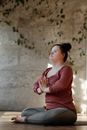 一名患有唐氏综合症的年轻女子在室内练习瑜伽，专注于内心的平静