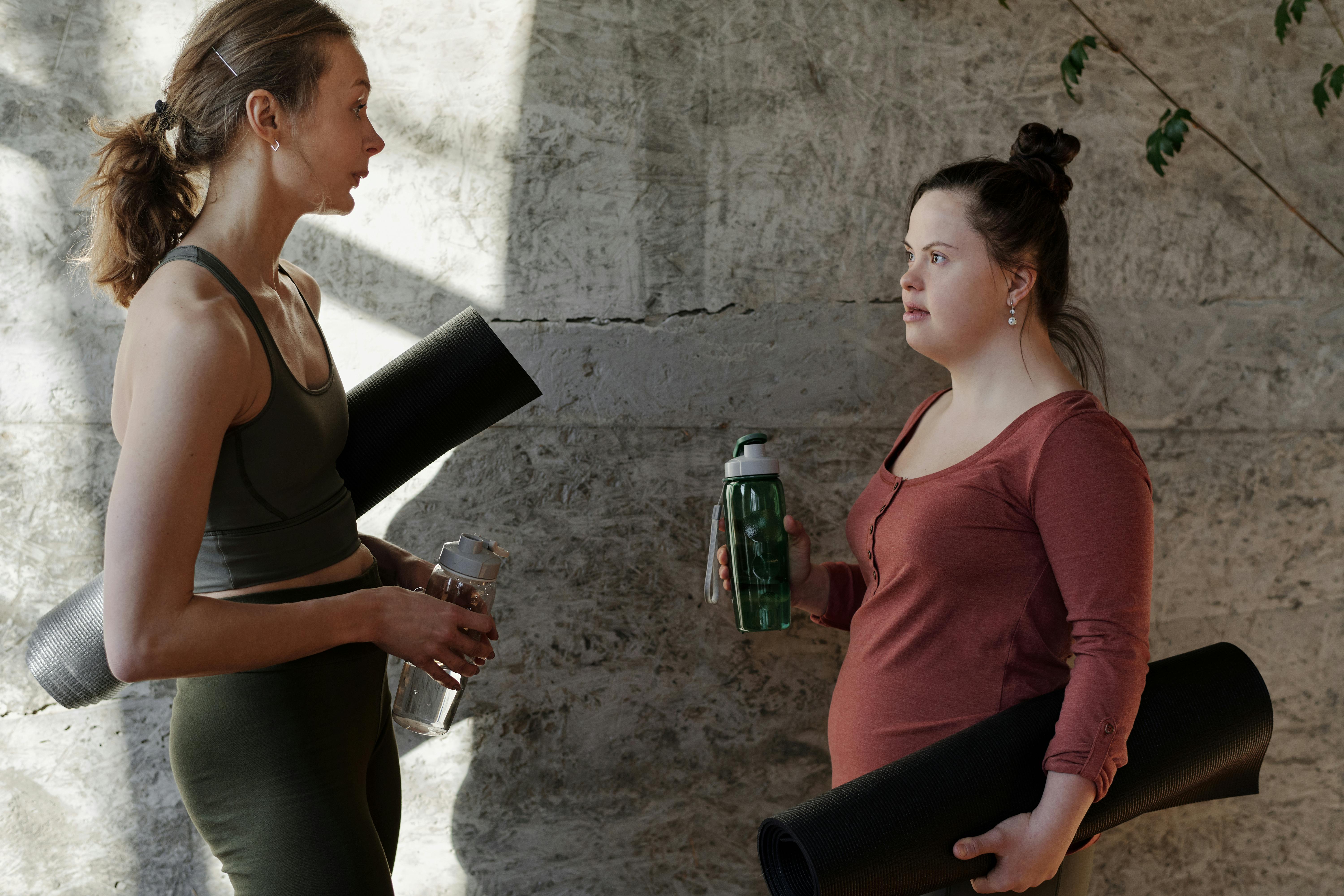 women holding their water bottles and yoga mats