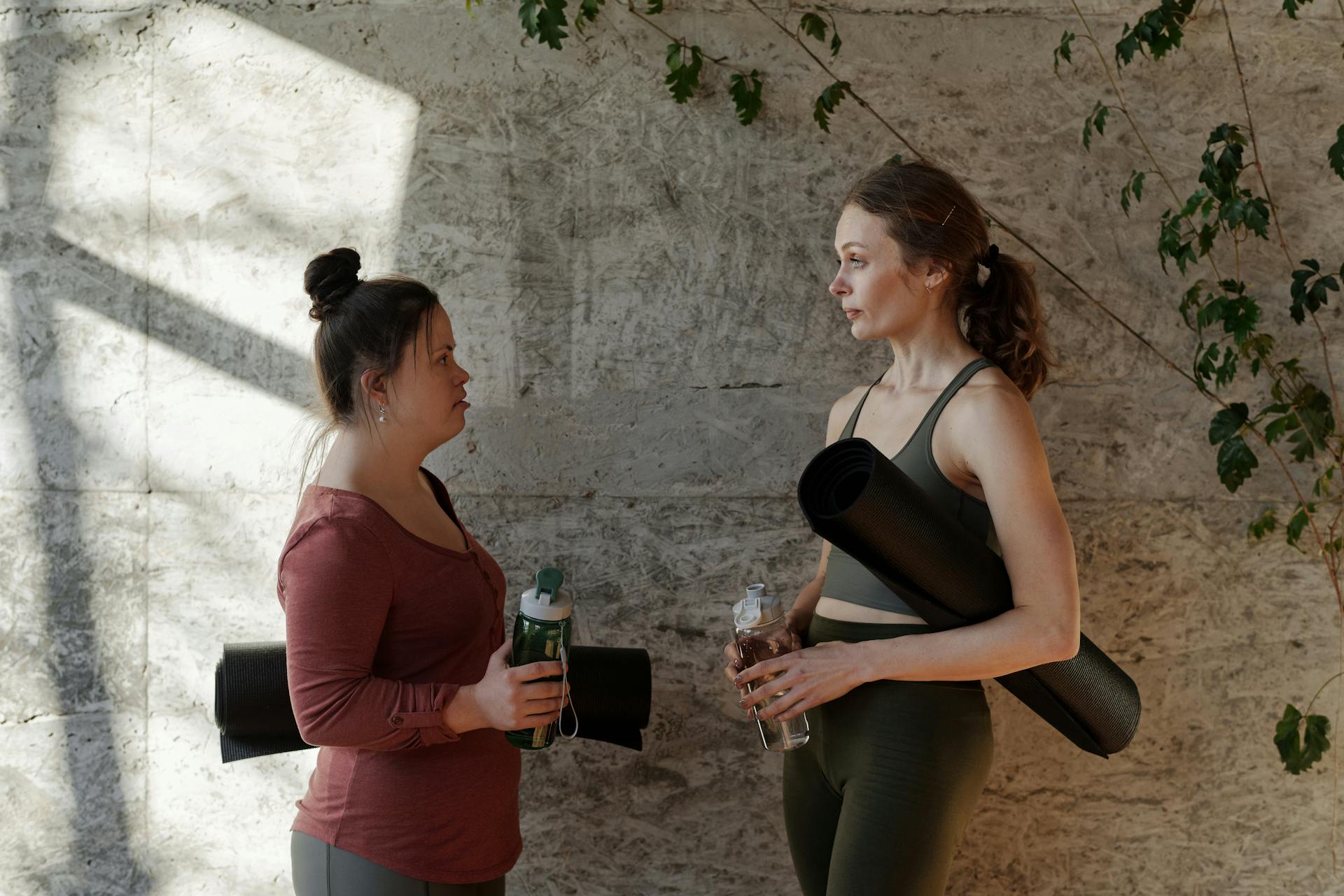 Two Women Holding Water Bottle and Yoga Mat