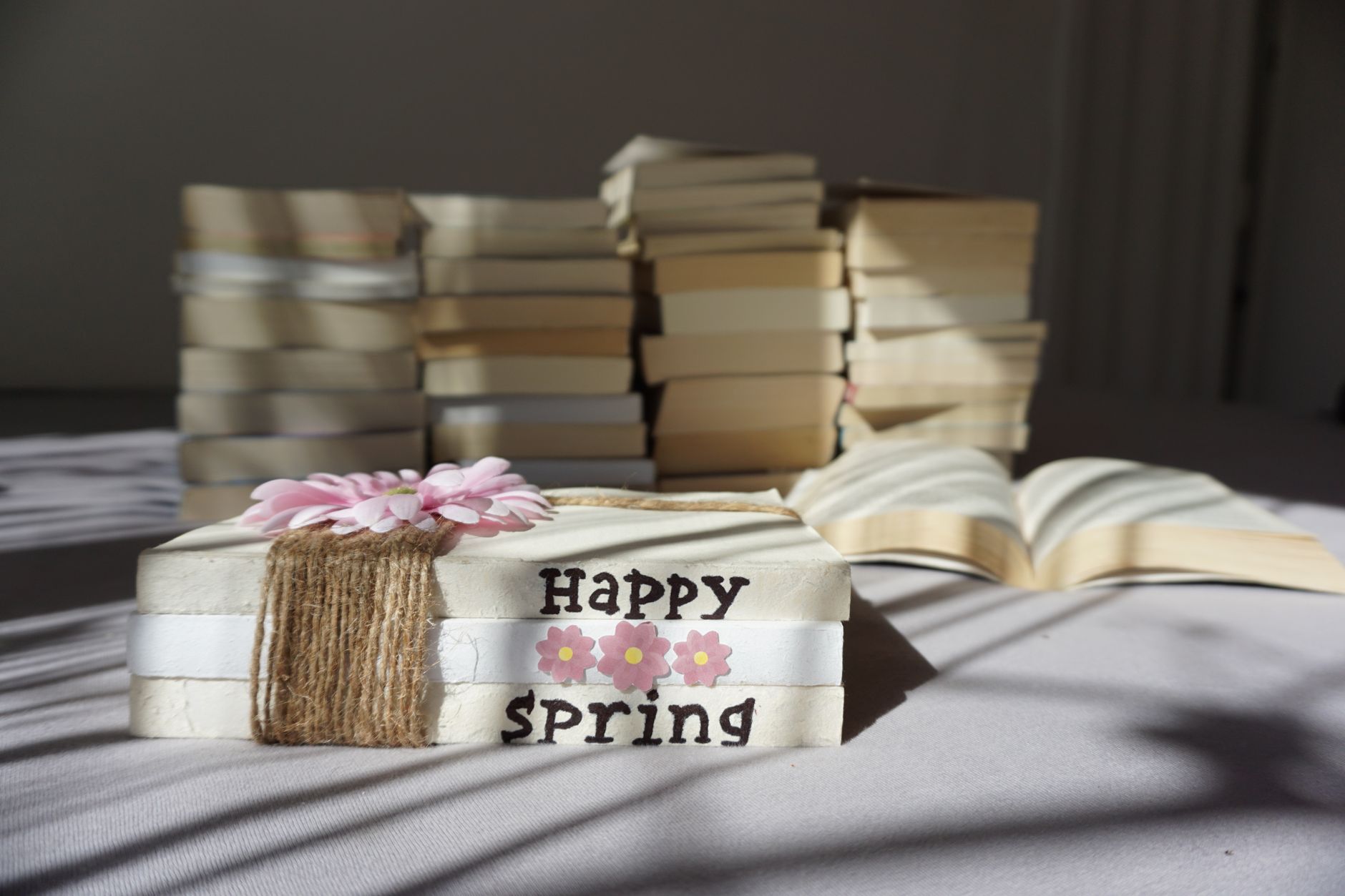 repurposed medicine book — A stack of books with a 'Happy Spring' message and floral decoration on a table.