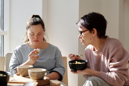 两名女性共进早餐，其中一人患有唐氏综合症，这促进了团结与关怀