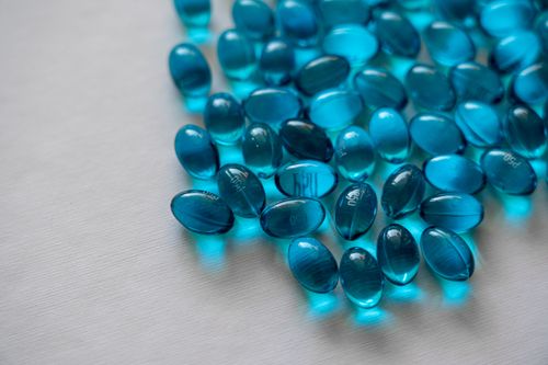 Free Close-up of blue gel capsules scattered on a white background, highlighting pharmaceutical themes. Stock Photo