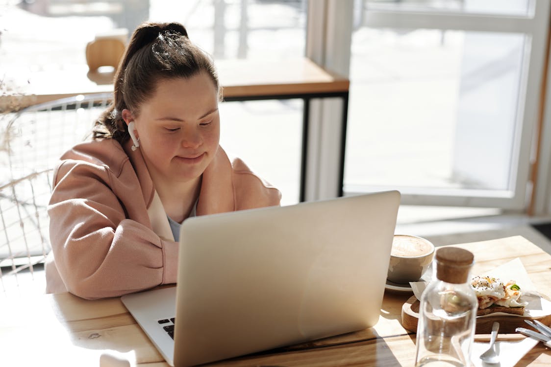 Free Young Girl Using A Laptop While Having Breakfast Stock Photo