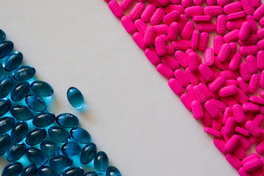 Close-up of blue gel capsules and pink tablets on a white background.