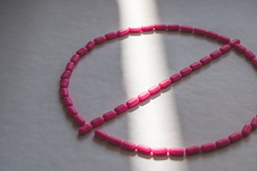 Pink pills arranged in a no-entry symbol under sunlight, symbolizing prohibition.