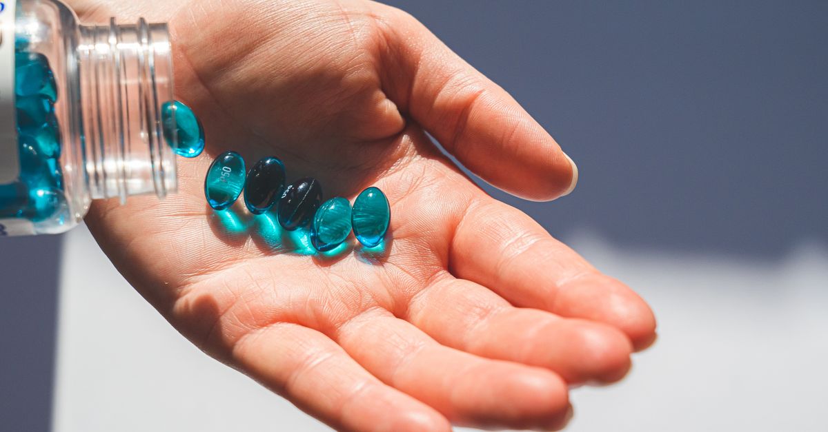 Blue gel capsules pouring from a bottle into an open hand, showcasing medication concept. - Evidence evidence guide for vitamin d sleep meta-analysis