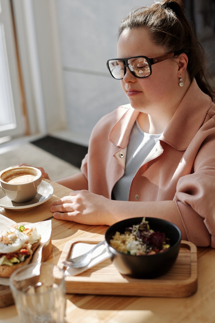 Woman Wearing Eyeglasses Near A Bowl Of Food And A Cup Of Coffee