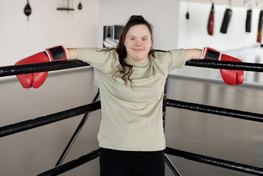 Young woman with Down syndrome wearing boxing gloves, smiling confidently in the gym.