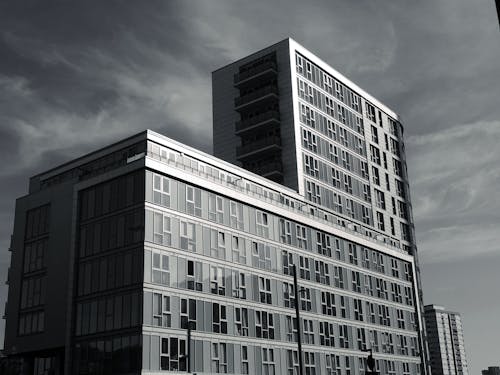 Grayscale Photo of Building Under Cloudy Day Sky