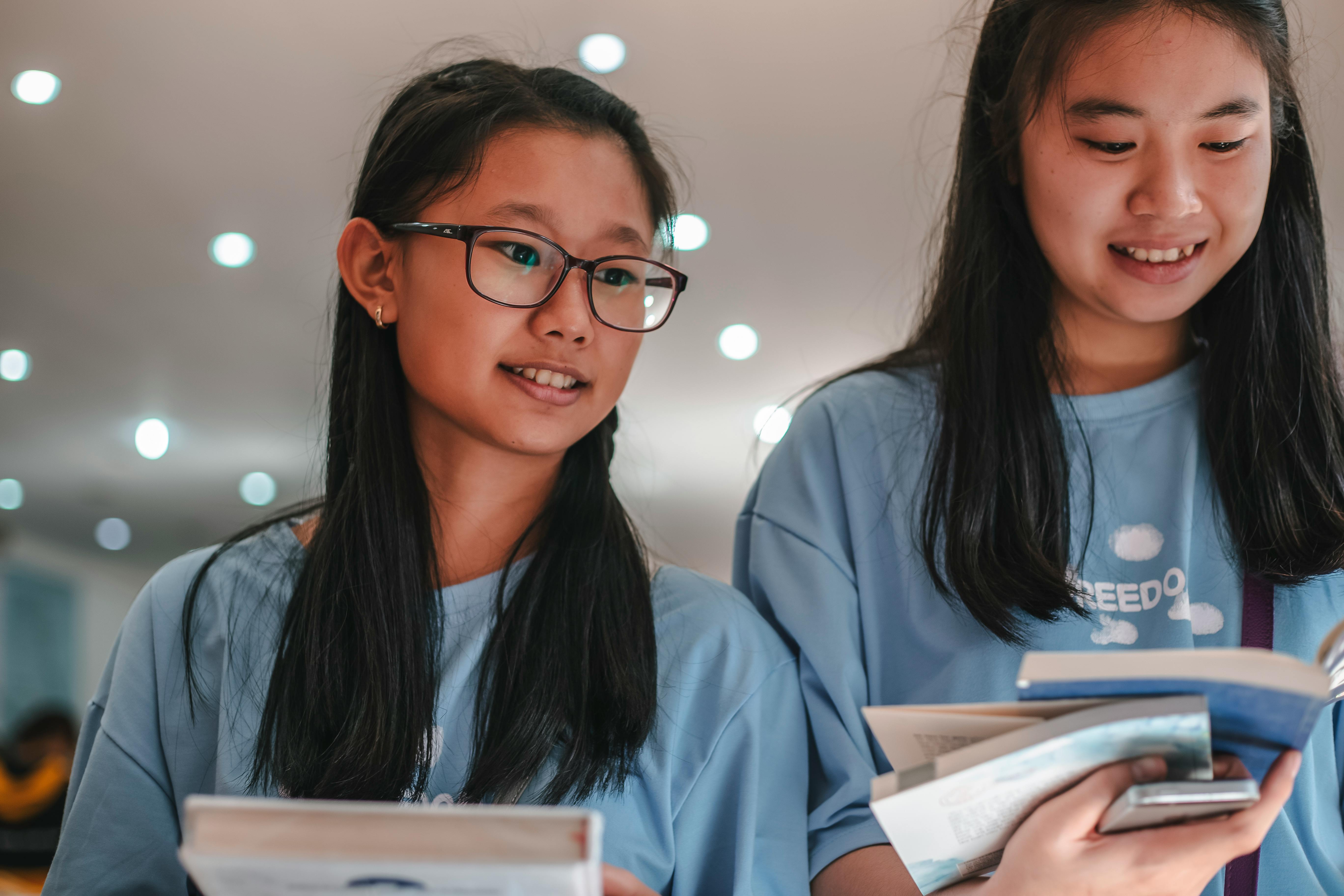 girls wearing blue shirt looking at the books