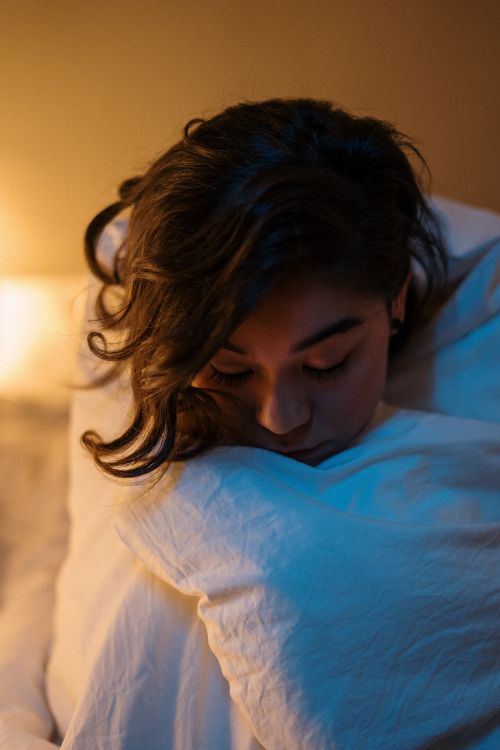 Free Woman in cozy bedroom environment, wrapped in warm blankets, enjoying a peaceful evening. Stock Photo