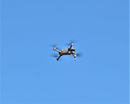 A drone flying through a clear blue sky, symbolizing technology and speed.