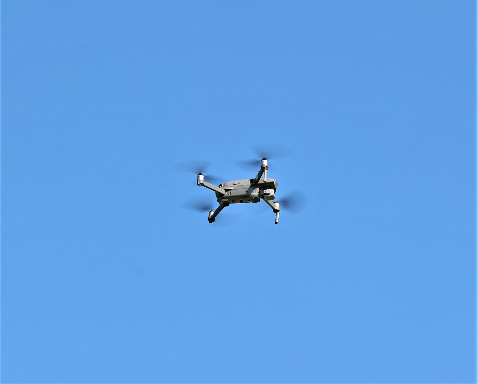 A drone flying through a clear blue sky, symbolizing technology and speed.