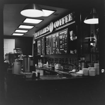 Black and white board with menu hanging over counter with dishware and appliances inside contemporary cafe