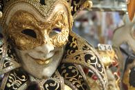 Closeup traditional elegant Venetian mask with golden ornaments hanging in vitrine of shop during carnival