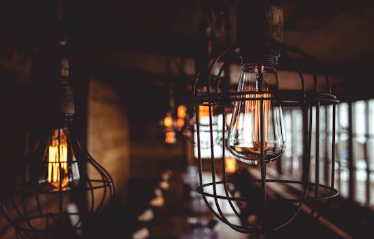 Cozy vintage-style indoor lighting with metal cage pendant lamps, softly glowing filament bulbs.