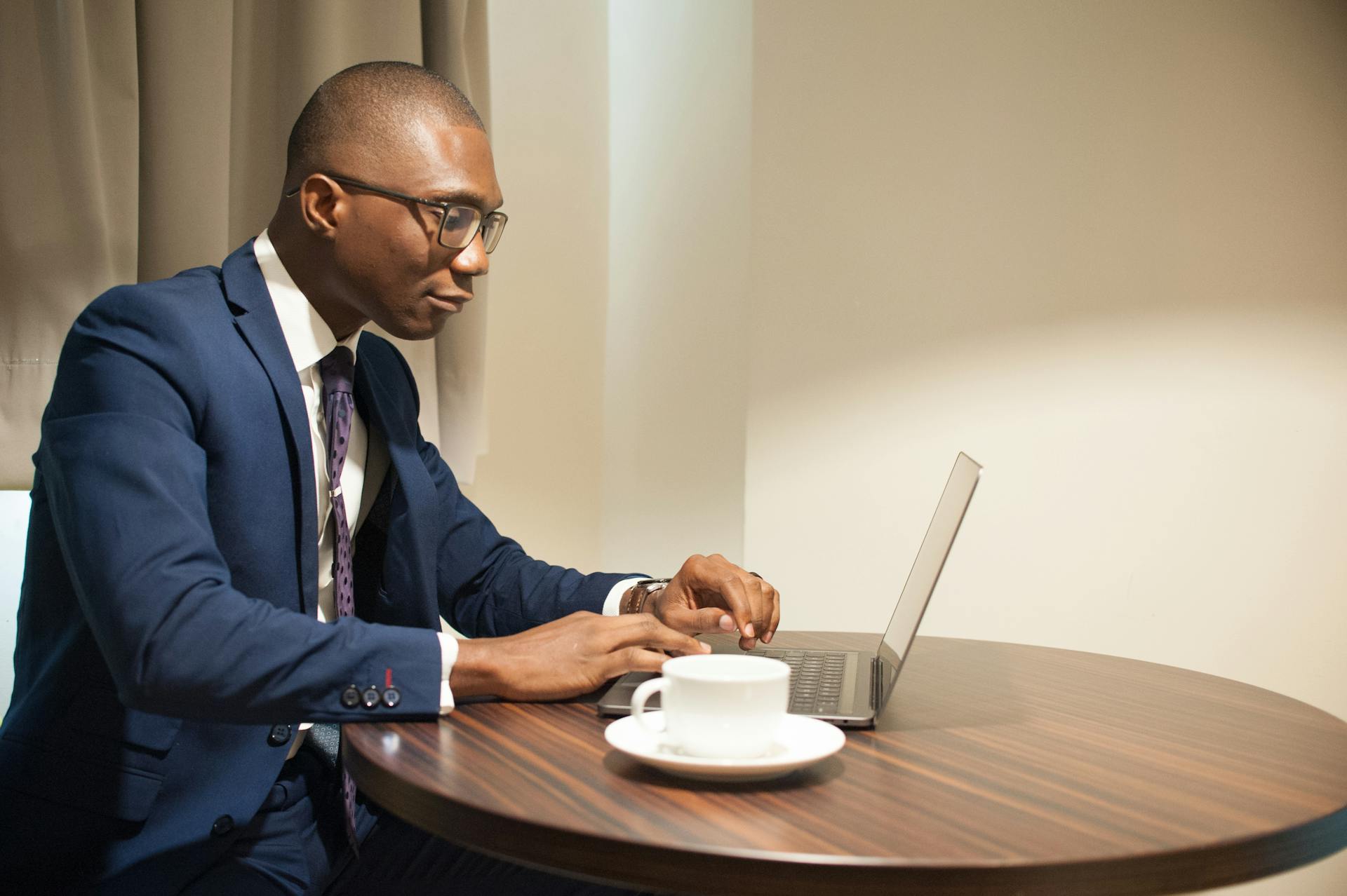 Man in Blue Suit Jacket Typing on His Laptop