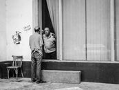 Black and white adult man standing outside shabby building and talking with policeman through window