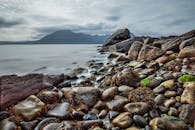 在壮丽的山脉映衬下，探索岩石海岸线上点缀的海藻，捕捉大自然的宁静之美