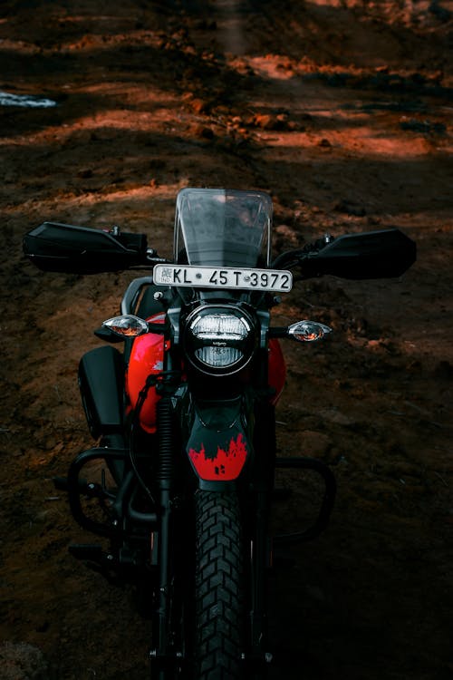 Black and Red Motorcycle Parked on Dirt Road