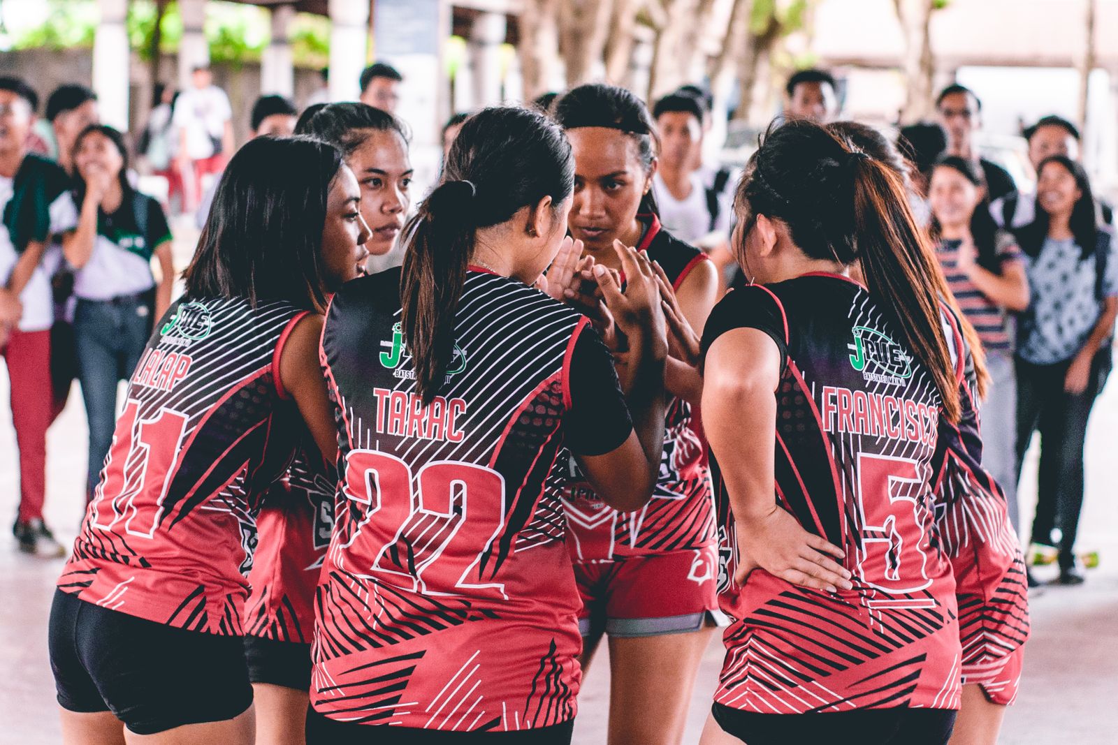 Women’s volleyball team in coordinated uniforms huddling on an indoor court