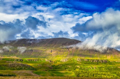 Free Vivid capture of a mountain landscape with lush greenery and dramatic clouds in Iceland. Stock Photo