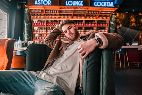 Man in Brown Coat Lying on Black Leather Couch