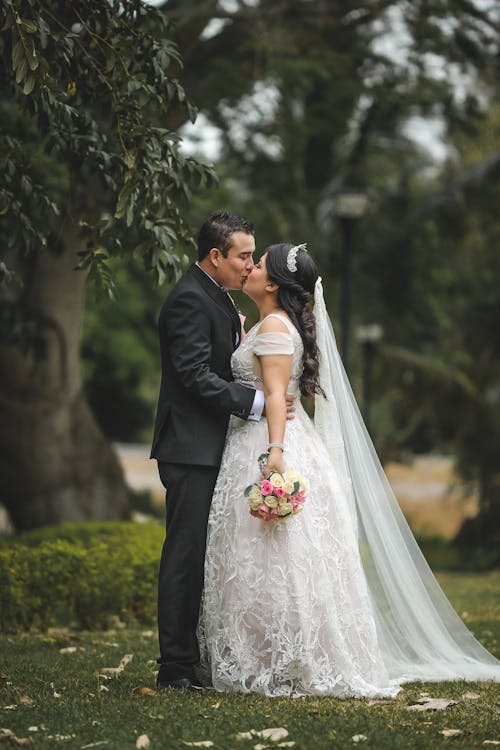 Free Man in Black Suit Kissing Woman in White Wedding Dress Stock Photo