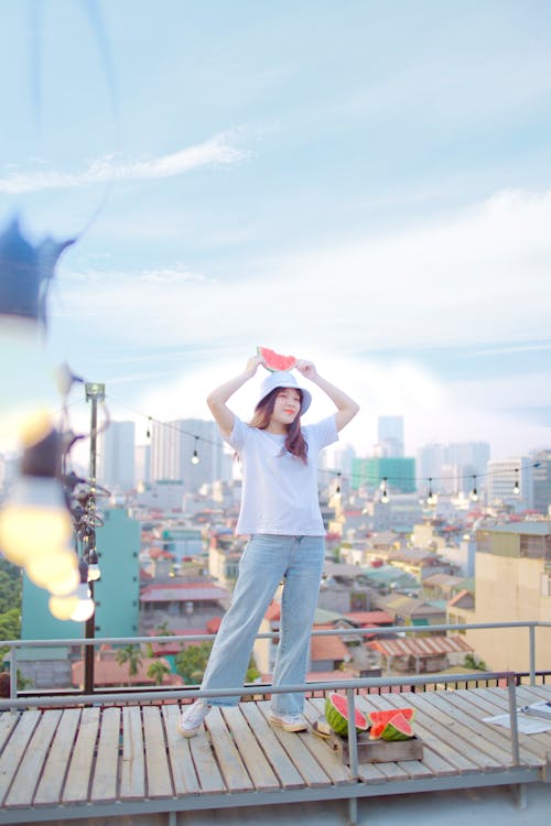 Woman in White T-shirt and Blue Denim Jeans Standing on Roof Top