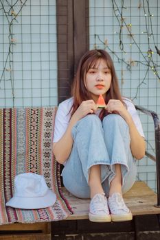 一位穿着休闲装的年轻女子正在户外享用西瓜