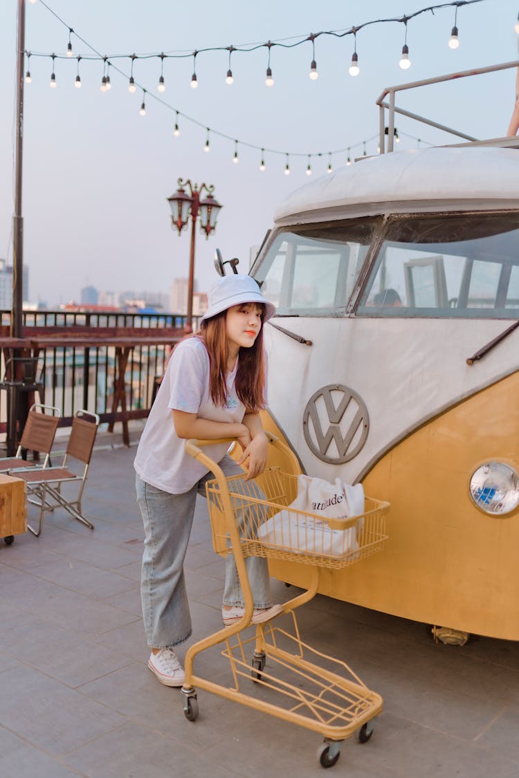 Young Asian Woman With Shopping Cart Near Retro Van