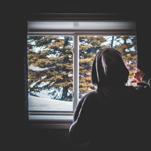 Unrecognizable guy looking out window