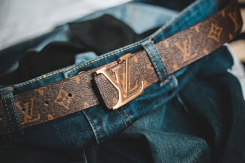 Closeup trendy leather belt with letters attached to modern stylish jeans at home