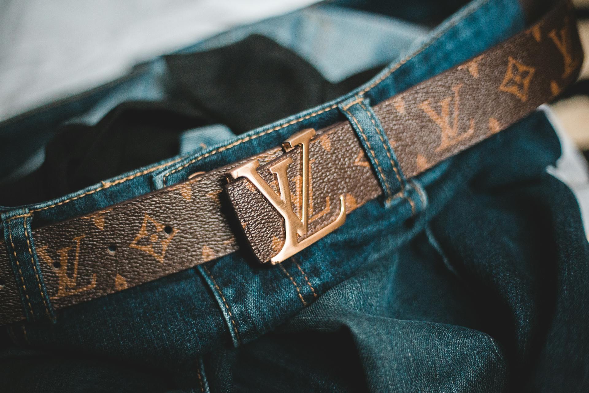 Closeup trendy leather belt with letters attached to modern stylish jeans at home